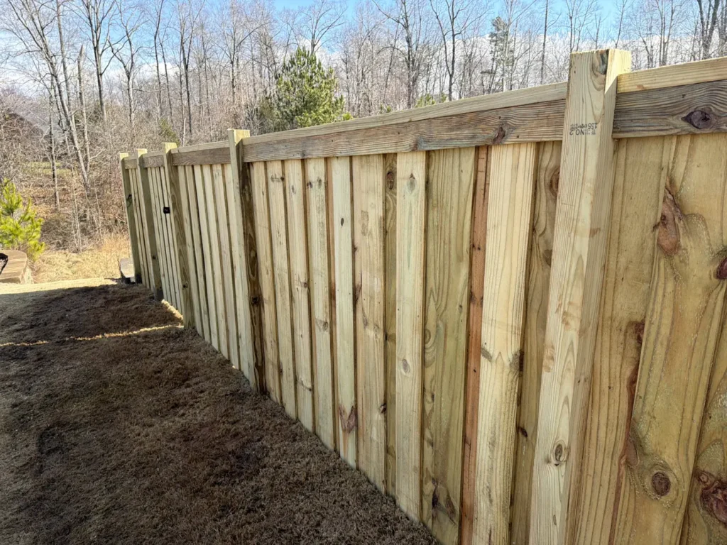 Wood privacy fence with a cap rail on a wooded lot
