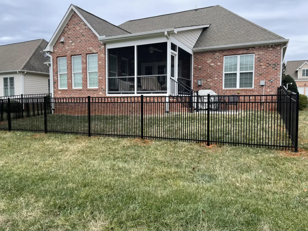 Black aluminum fence enclosing the backyard of a brick ranch home