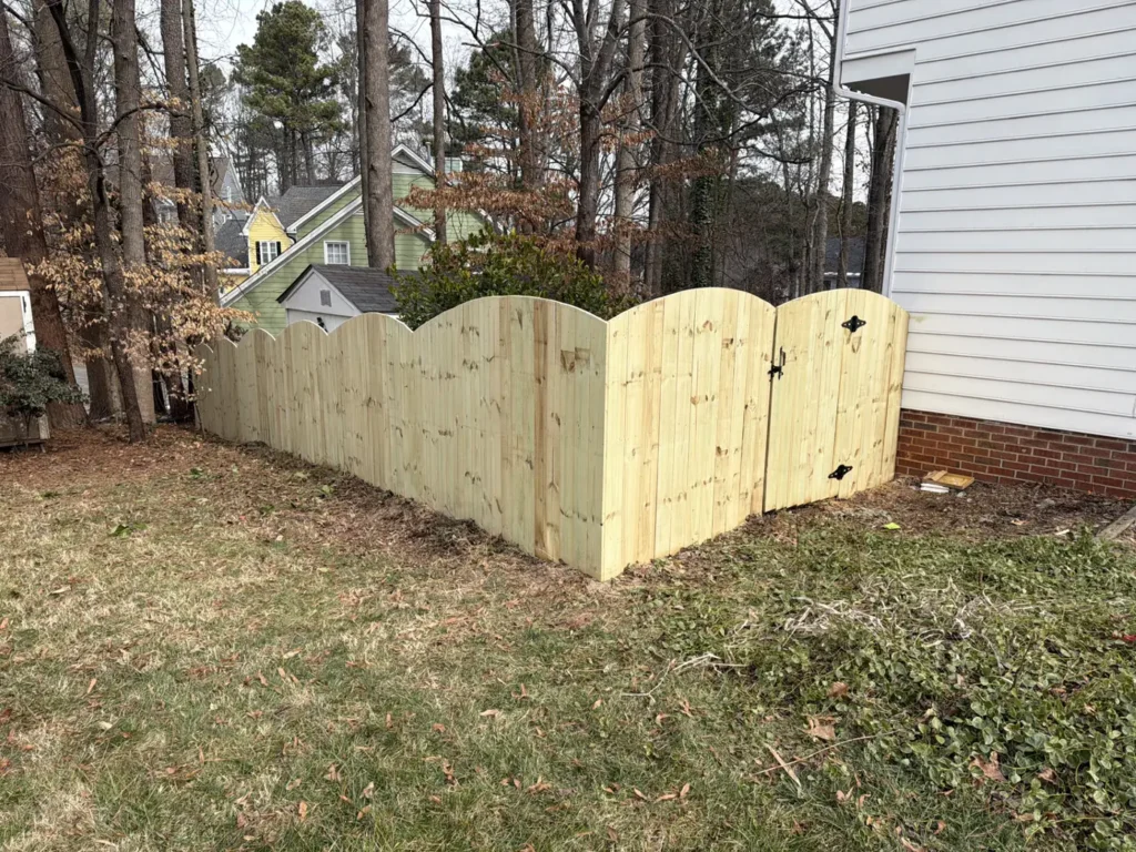 Wood privacy fence with a scalloped-top double gate