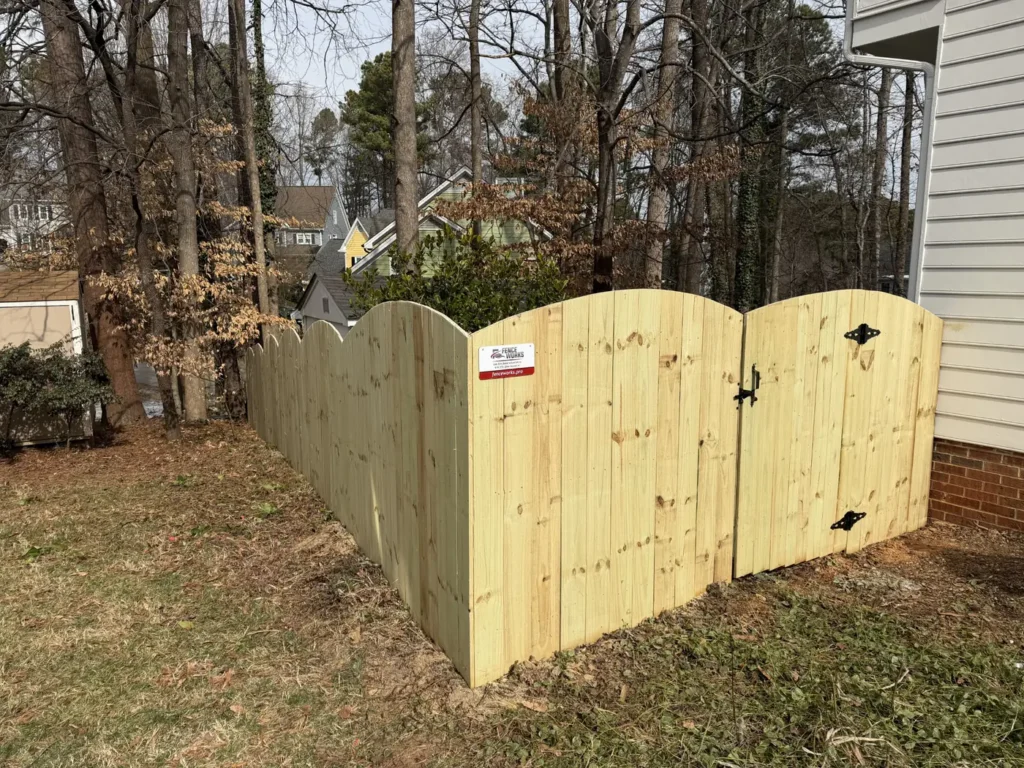 Custom wood double gate with an arched top on a privacy fence