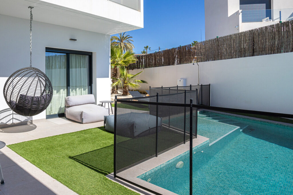 Backyard swimming pool enclosed by a black mesh pool safety fence
