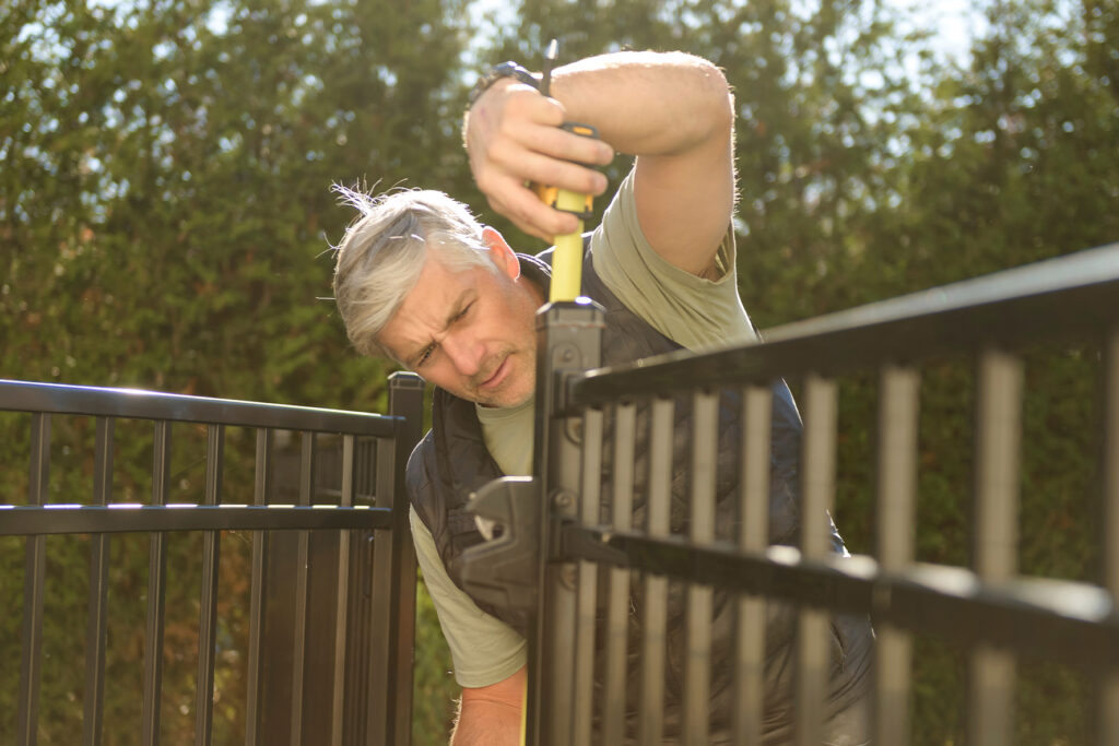 Installer adjusting a black metal pool fence panel