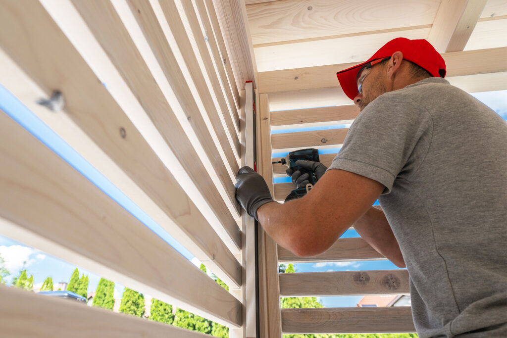 Installer fastening horizontal wood boards to a post during a spring fence installation