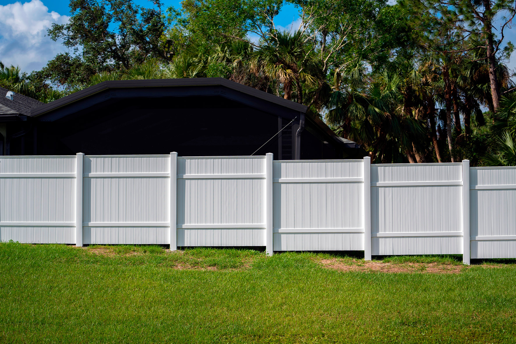 A white fence made of premium vinyl is positioned in front of a house, highlighting its quality over big box alternatives.