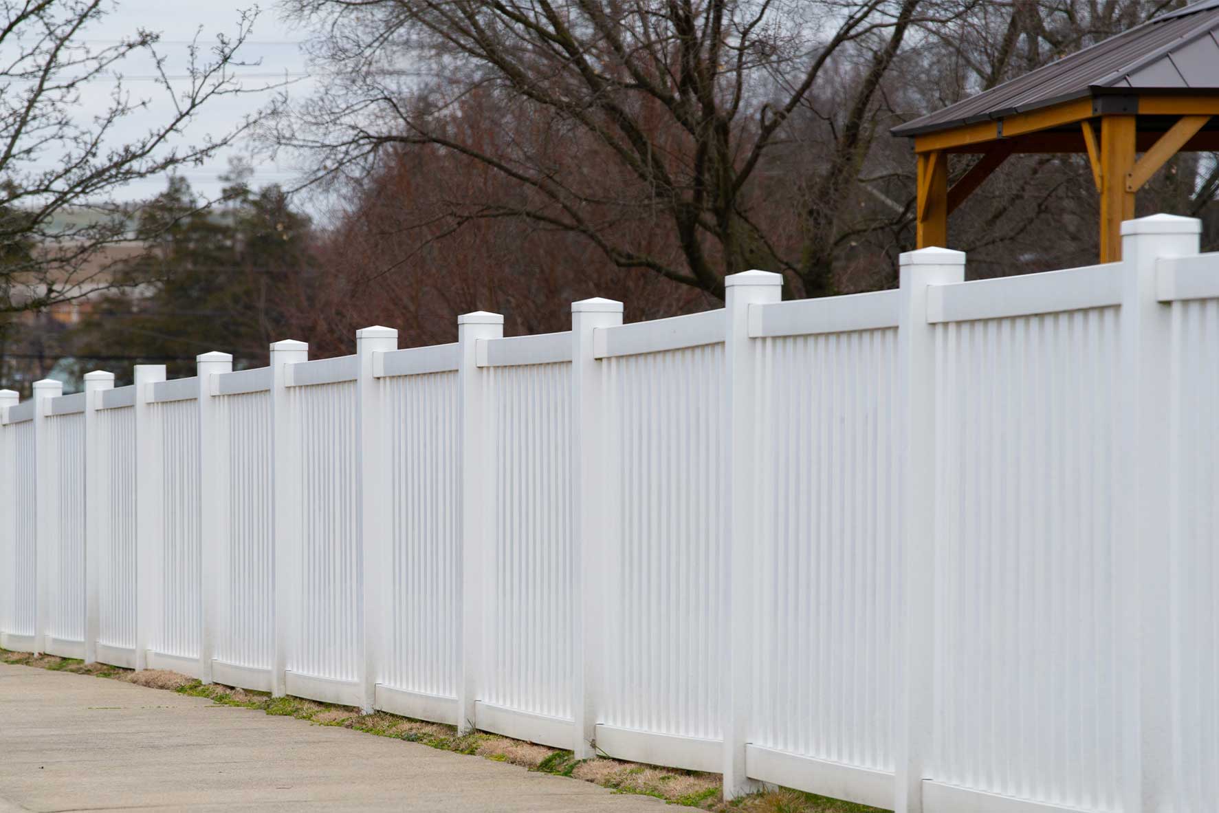 A white fence borders a house, serving as a visual guide for new homeowners on property fencing options.