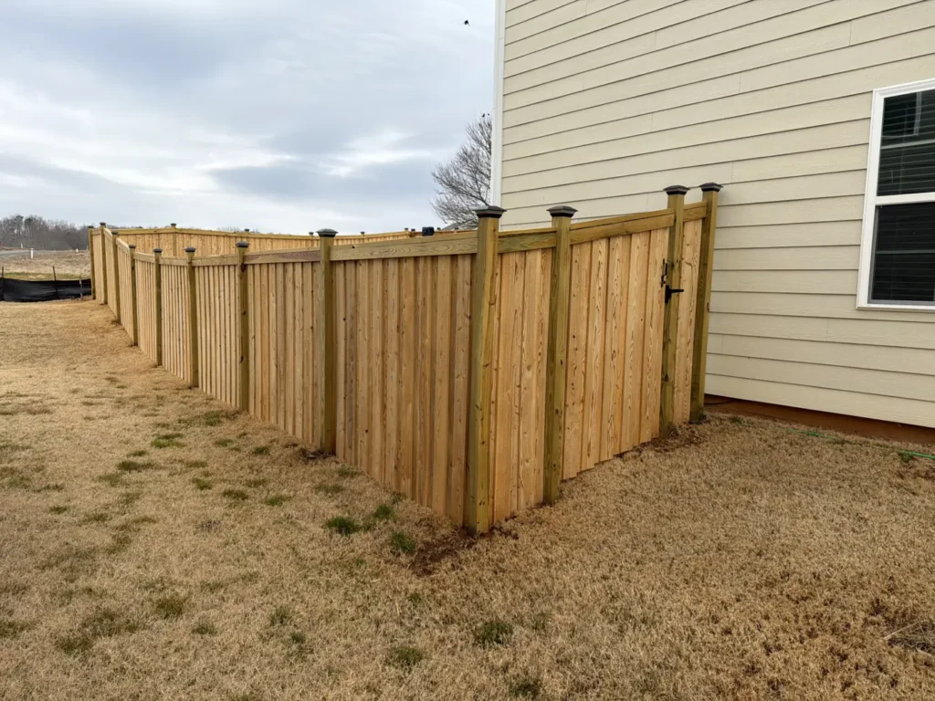 Wood privacy fence with a cap rail and evenly set posts stepping down a side yard