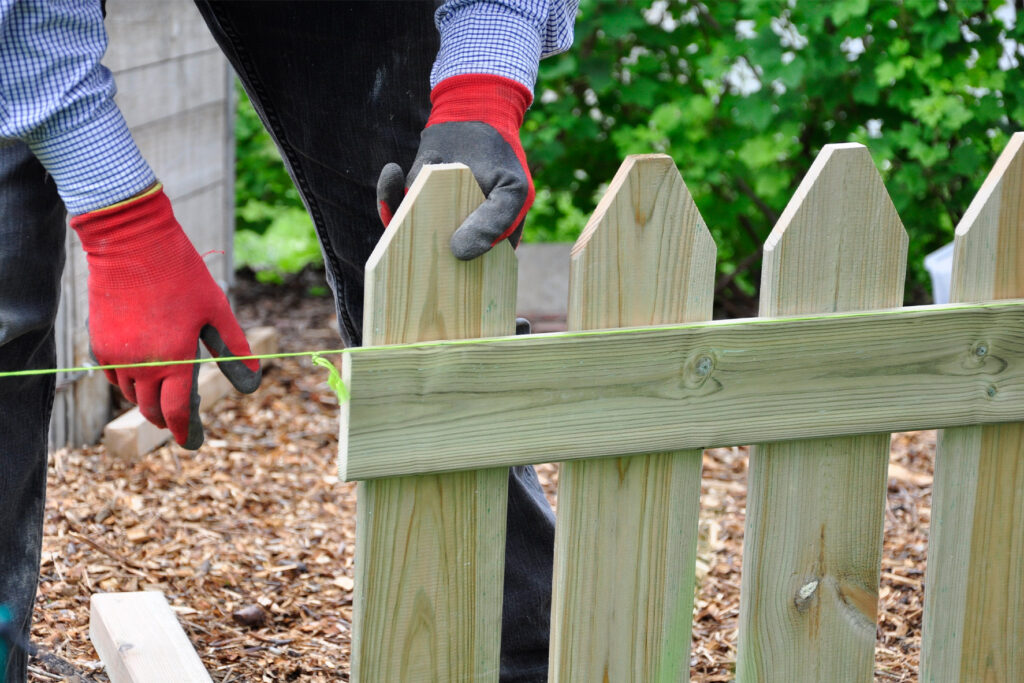 Installer using a string line to align pressure-treated pine pickets