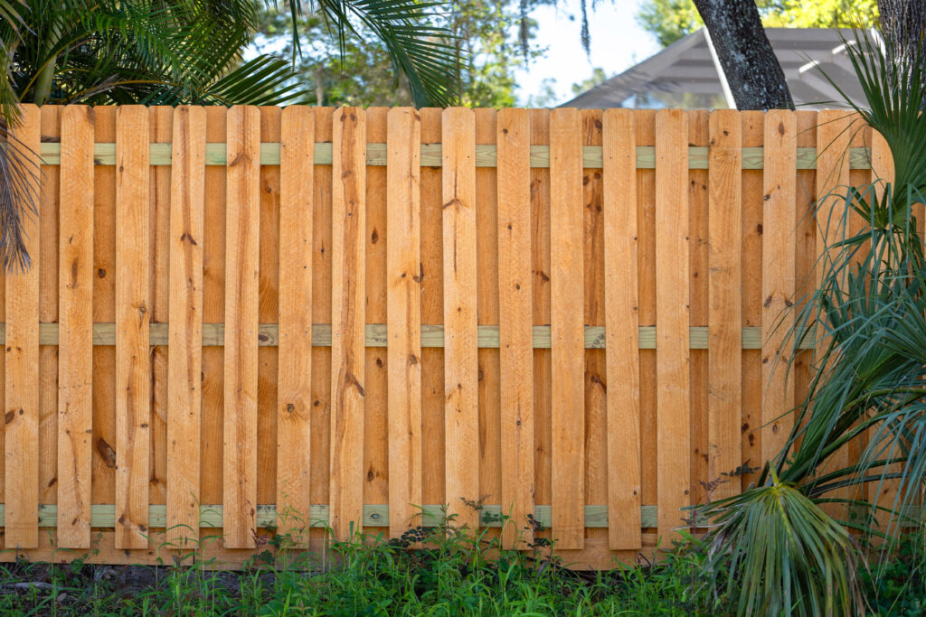 Shadowbox-style wood privacy fence with alternating pine boards